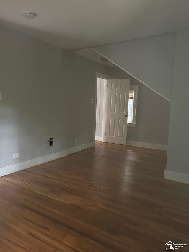 interior space with dark wood-type flooring, visible vents, and baseboards