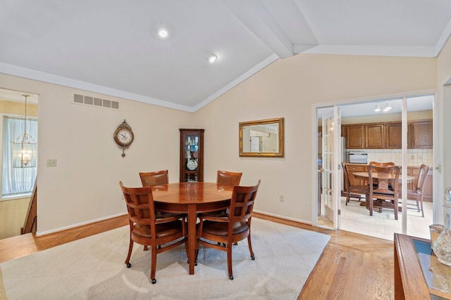 dining space featuring a chandelier, vaulted ceiling with beams, and light hardwood / wood-style flooring