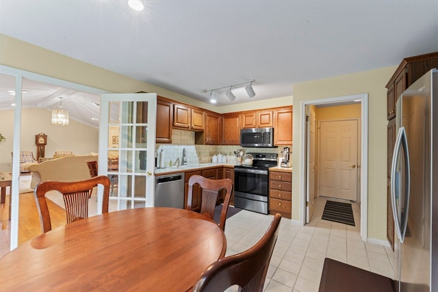 kitchen featuring sink, a notable chandelier, decorative light fixtures, decorative backsplash, and appliances with stainless steel finishes