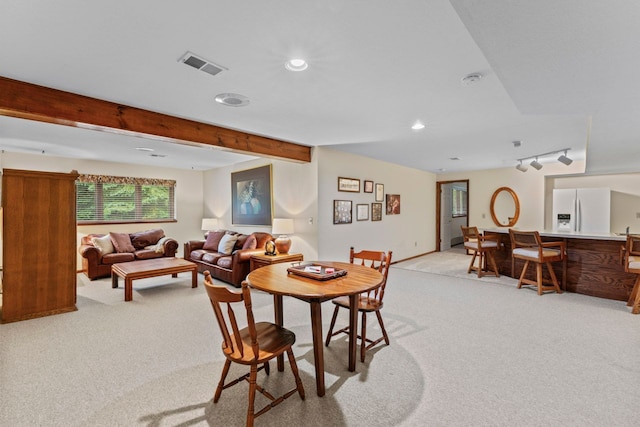 carpeted dining room with beam ceiling and rail lighting