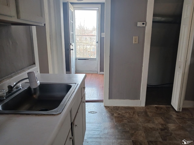 639 Michigan Ave, Monroe, MI 48162 - kitchen with stone finish floor, white cabinetry, baseboards, and a sink