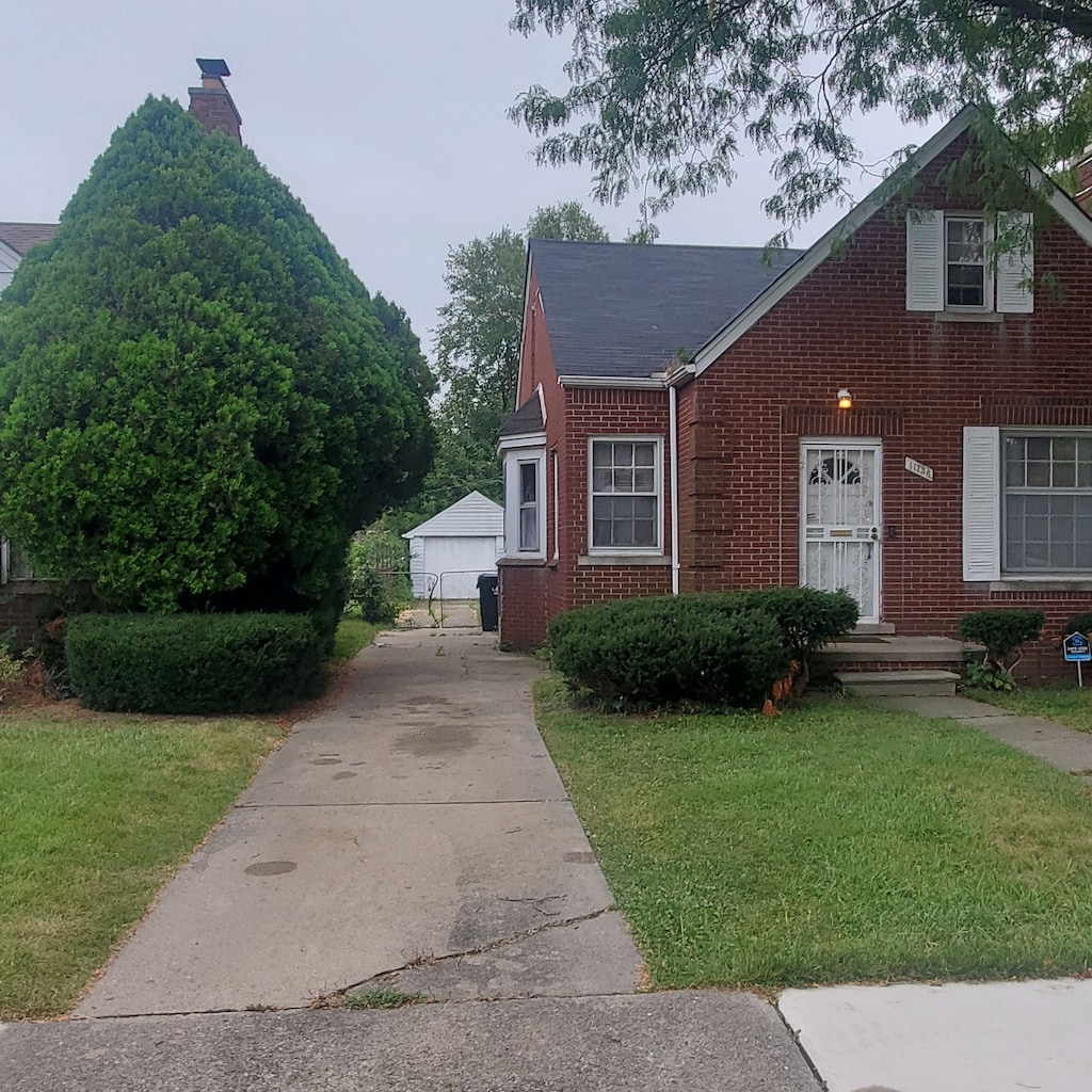 view of front of property featuring an outbuilding, a garage, and a front lawn