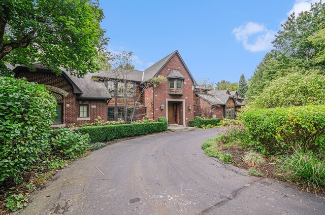 26061 Hawthorne Dr, Franklin, MI 48025 - tudor-style house with brick siding, driveway, and roof with shingles