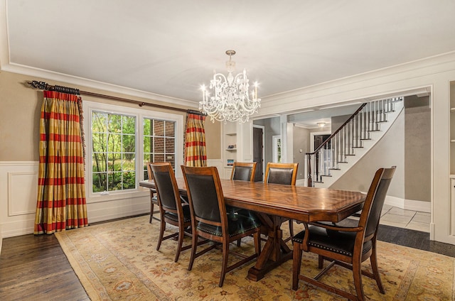 dining space featuring wood-type flooring, ornamental molding, and an inviting chandelier