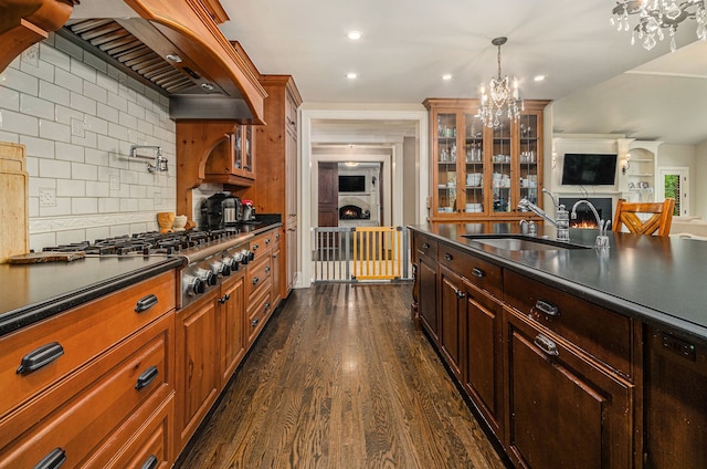 kitchen with decorative backsplash, custom range hood, dark wood-type flooring, sink, and a notable chandelier