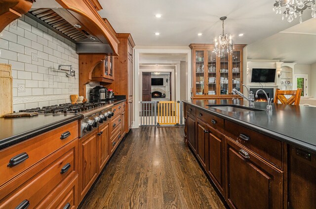 26061 Hawthorne Dr, Franklin, MI 48025 - kitchen featuring a chandelier, a sink, dark countertops, stainless steel gas stovetop, and glass insert cabinets