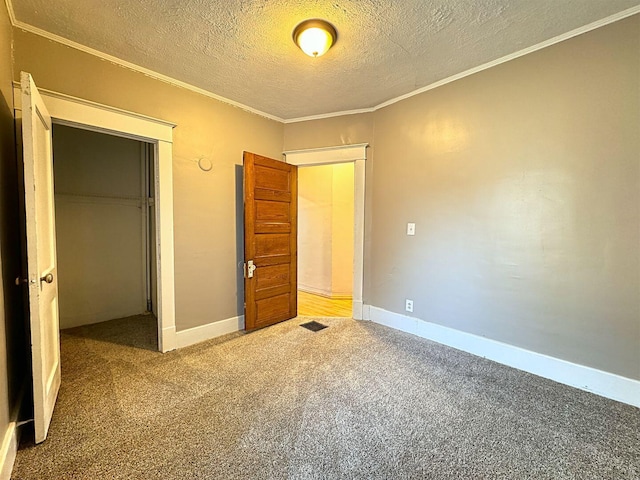 unfurnished bedroom featuring a textured ceiling, carpet floors, a closet, and crown molding