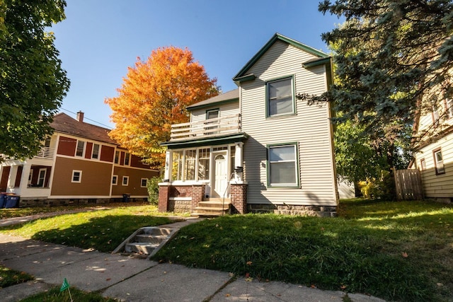 view of front of house featuring a balcony and a front lawn