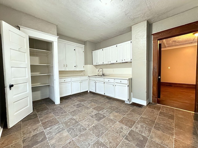 kitchen featuring a textured ceiling, dark hardwood / wood-style flooring, white cabinetry, and sink