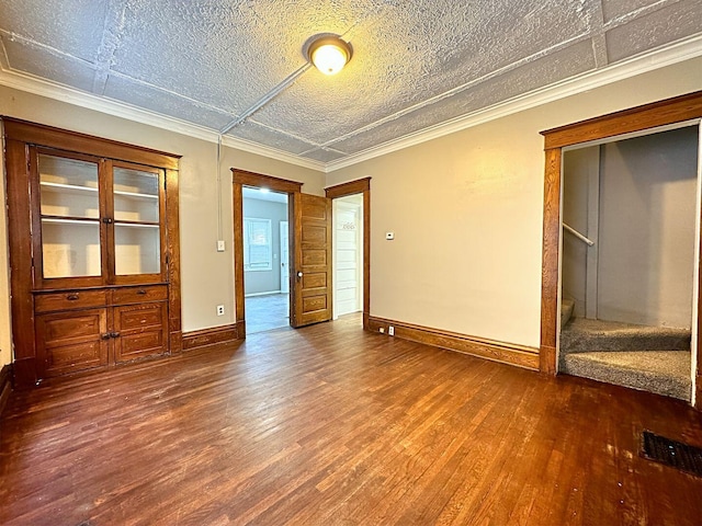 unfurnished bedroom featuring crown molding, dark hardwood / wood-style flooring, and a textured ceiling