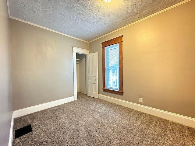 unfurnished bedroom featuring a closet, carpet, a textured ceiling, and ornamental molding