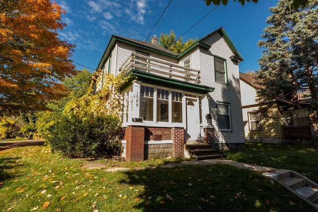 view of front of home with a balcony and a front lawn