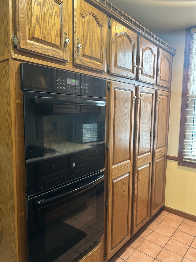 kitchen featuring black double oven and light tile patterned flooring