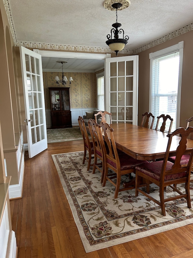 dining space with a notable chandelier, dark hardwood / wood-style flooring, a textured ceiling, and french doors