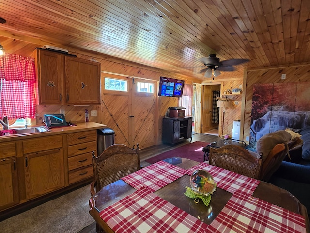 carpeted dining area featuring wooden ceiling, wood walls, and sink