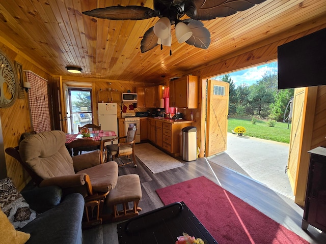 living room featuring dark hardwood / wood-style flooring, ceiling fan, and wooden walls