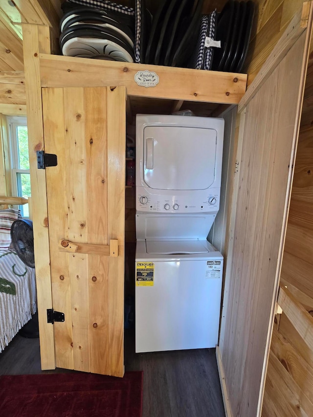 laundry room featuring dark hardwood / wood-style flooring and stacked washer and clothes dryer