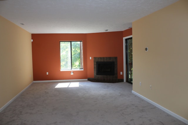 unfurnished living room featuring carpet flooring, a textured ceiling, and a tile fireplace