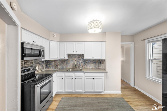 kitchen with white cabinets, appliances with stainless steel finishes, light hardwood / wood-style floors, and sink