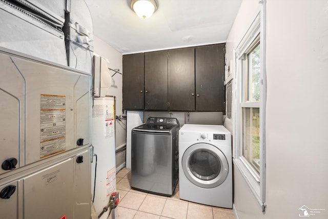 laundry area featuring water heater, washer and dryer, light tile patterned flooring, and cabinets