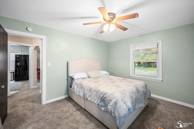 bedroom with ceiling fan, light colored carpet, and black refrigerator with ice dispenser