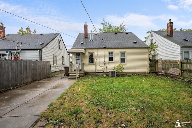 back of house with central AC unit and a lawn