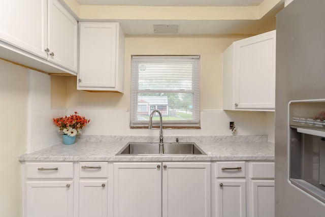 kitchen featuring white cabinets, stainless steel fridge, sink, and tasteful backsplash