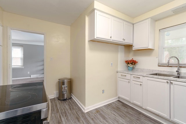 kitchen featuring white cabinets, sink, stainless steel stove, and light wood-type flooring