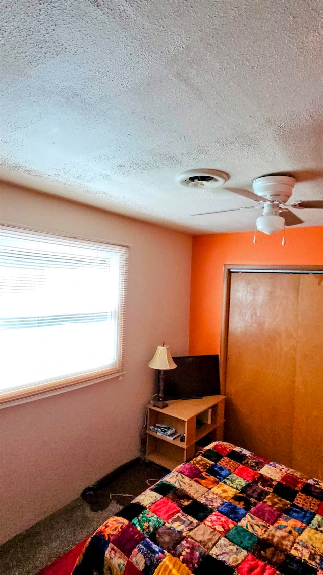 bedroom with carpet, a textured ceiling, and ceiling fan