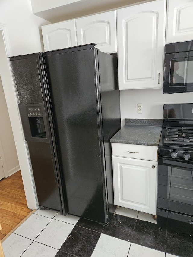 kitchen with white cabinetry, tile patterned flooring, and black appliances