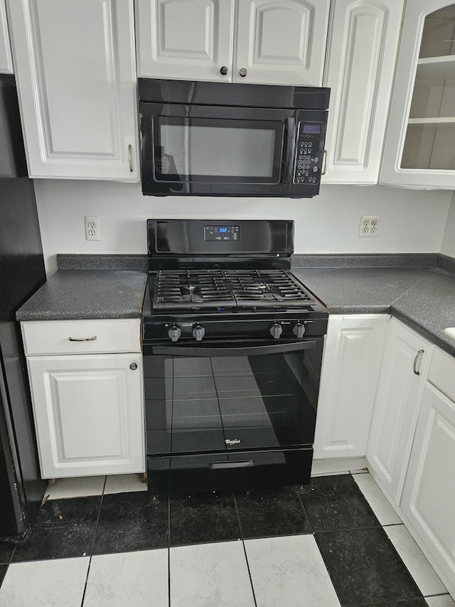 kitchen featuring dark tile patterned floors, black appliances, and white cabinets