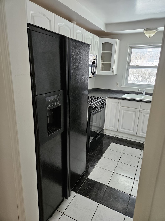 kitchen with white cabinetry, dark tile patterned flooring, sink, and black appliances