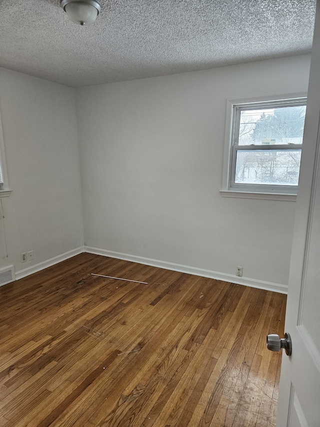 unfurnished room featuring dark hardwood / wood-style flooring and a textured ceiling