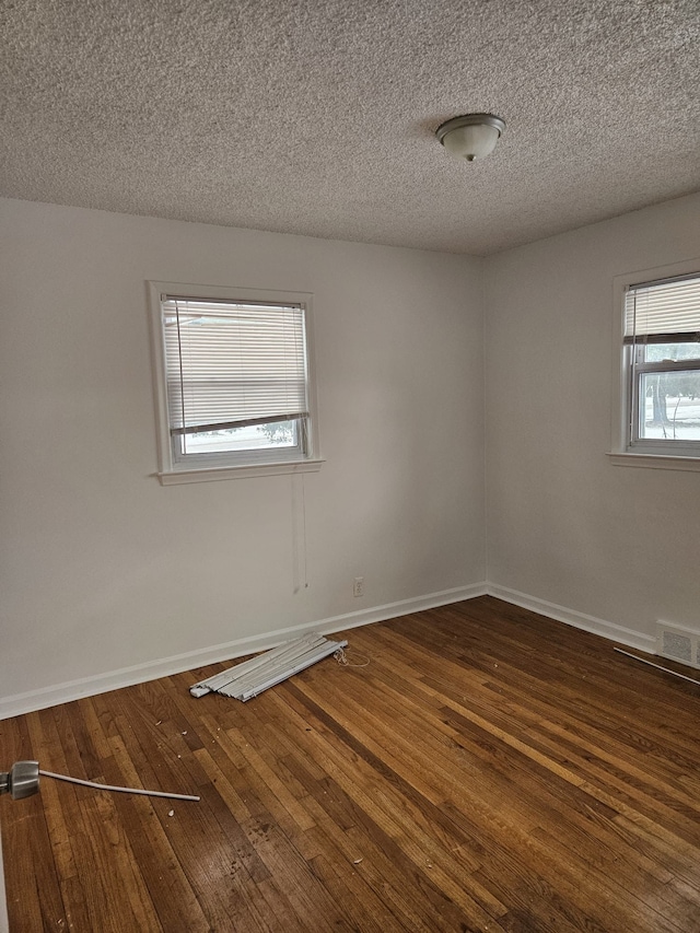 empty room with dark hardwood / wood-style flooring and a textured ceiling