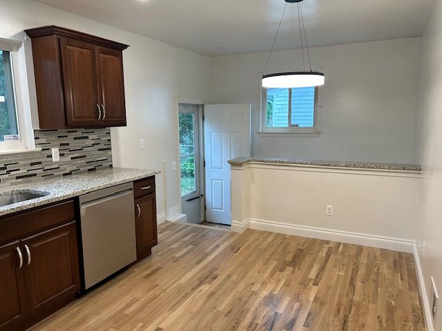 kitchen with dishwasher, hanging light fixtures, a wealth of natural light, and light hardwood / wood-style flooring