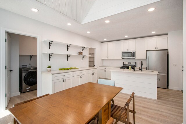 kitchen featuring white cabinetry, stainless steel appliances, and washer / dryer