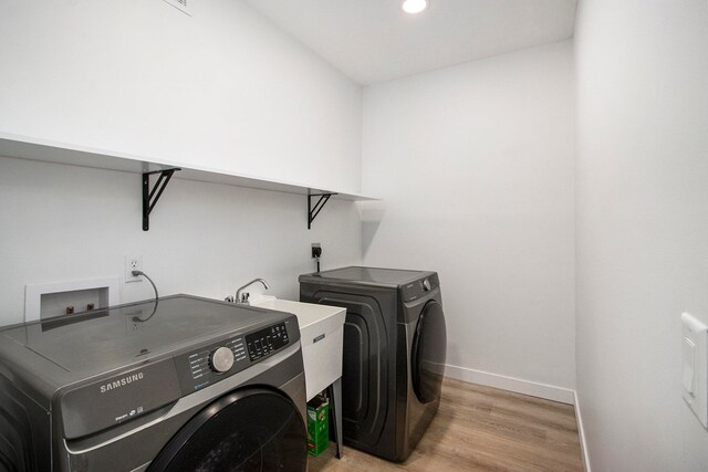 washroom with sink, washing machine and dryer, and light hardwood / wood-style flooring