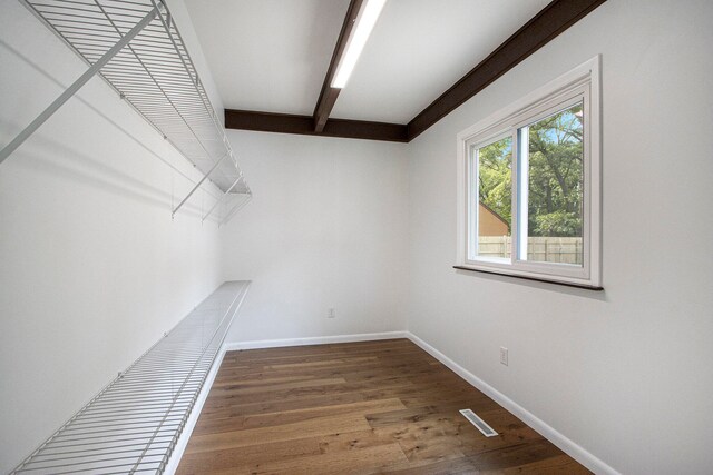 walk in closet with hardwood / wood-style floors and beam ceiling