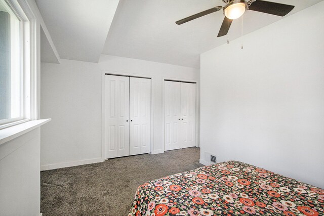 bedroom with two closets, ceiling fan, and carpet