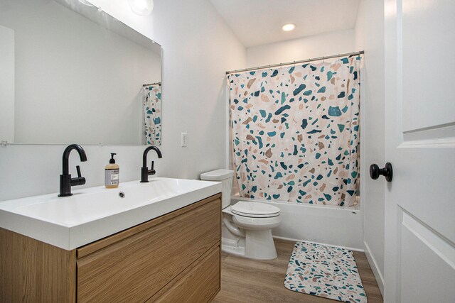 full bathroom featuring hardwood / wood-style flooring, vanity, shower / tub combo with curtain, and toilet