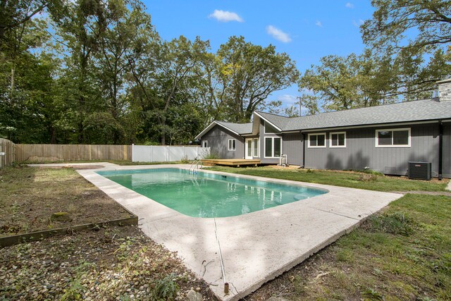 view of swimming pool featuring a lawn, a deck, and central air condition unit