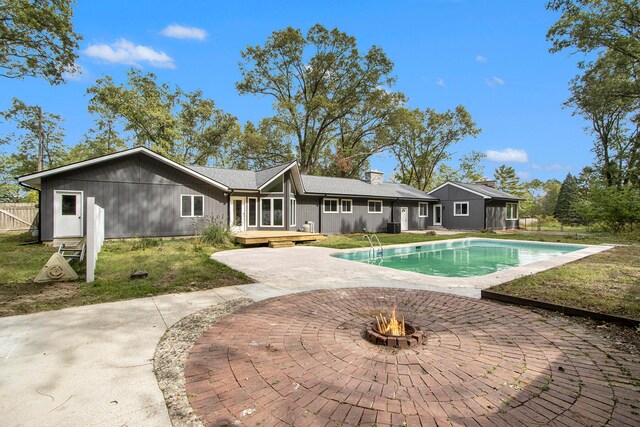 back of property with a swimming pool side deck and an outdoor fire pit