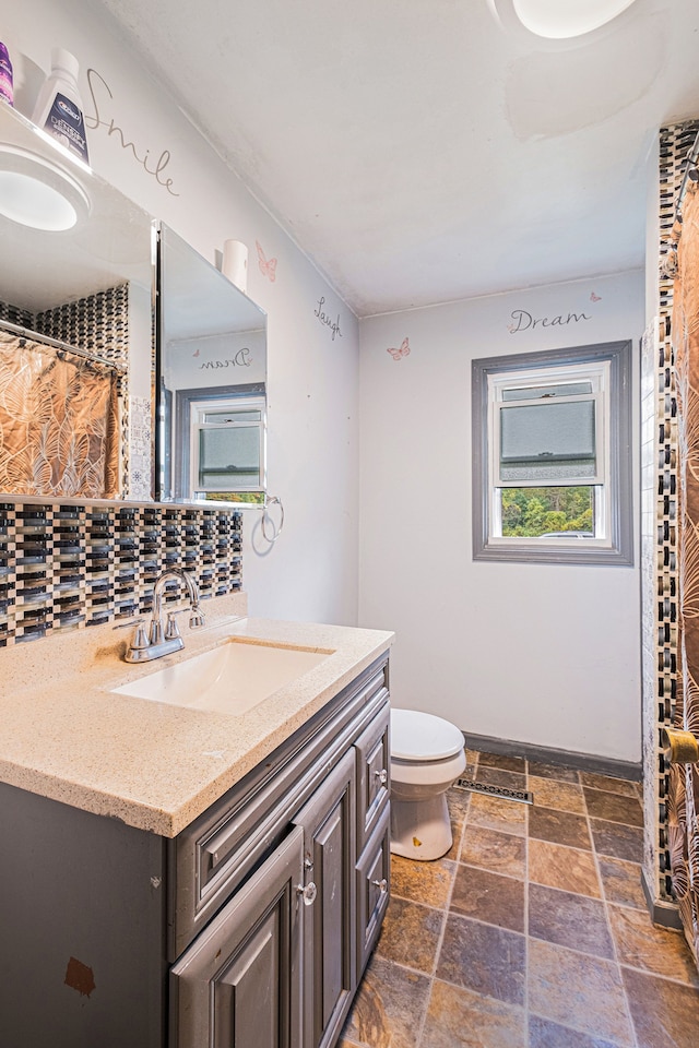 bathroom featuring decorative backsplash, toilet, and vanity