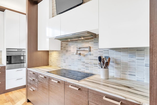 kitchen featuring white cabinetry, light hardwood / wood-style flooring, backsplash, oven, and black electric cooktop