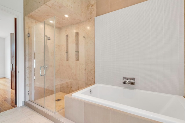 bathroom featuring wood-type flooring, tile walls, and independent shower and bath