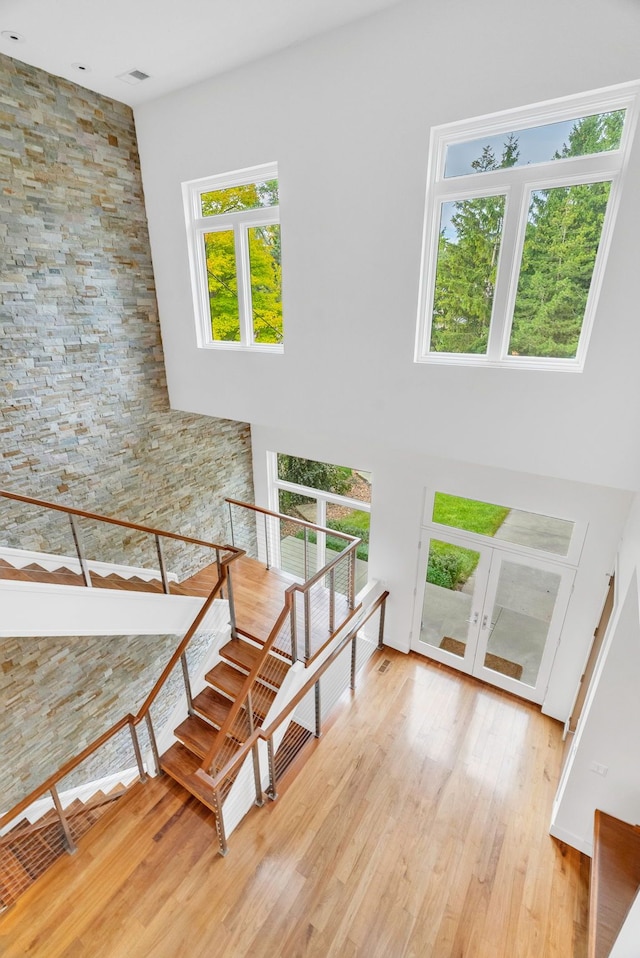 stairway featuring hardwood / wood-style floors, a towering ceiling, and french doors