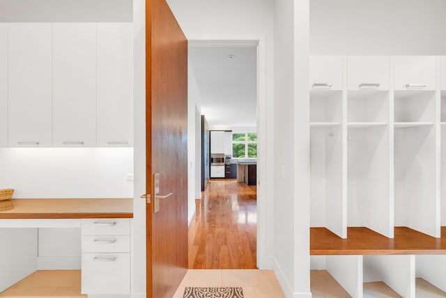 mudroom with built in desk and light hardwood / wood-style floors