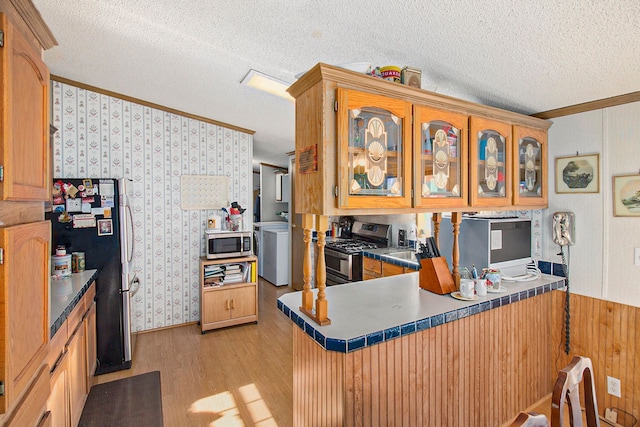 kitchen featuring kitchen peninsula, light hardwood / wood-style flooring, stainless steel appliances, and a textured ceiling