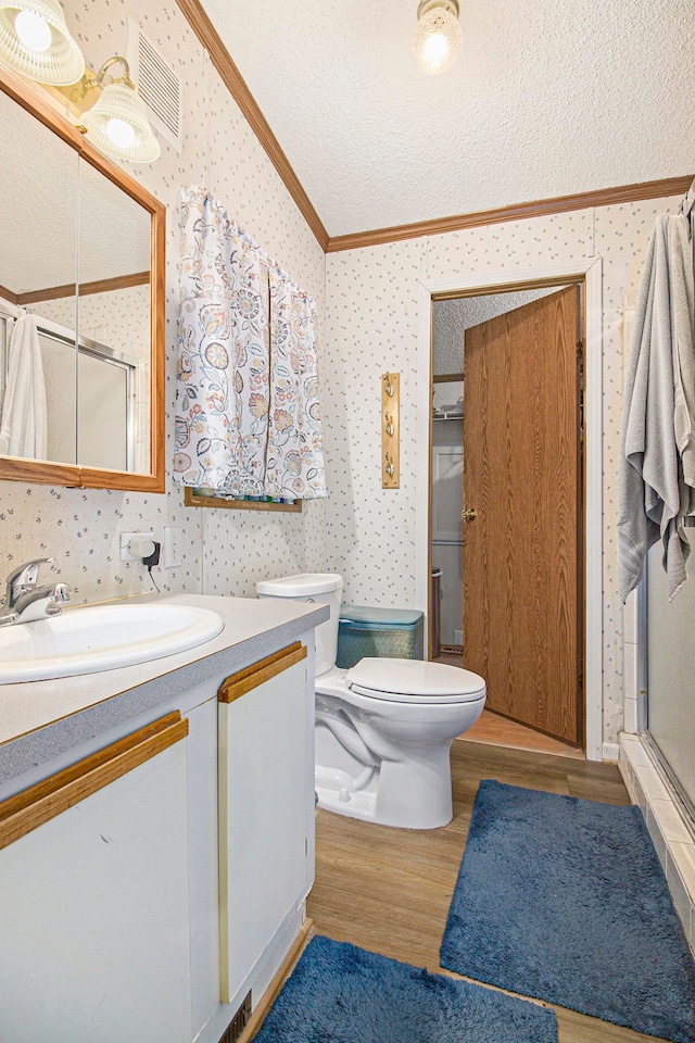 bathroom featuring vanity, a textured ceiling, a shower with door, crown molding, and hardwood / wood-style floors