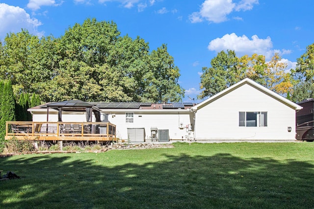 back of house featuring solar panels, central air condition unit, a lawn, and a wooden deck